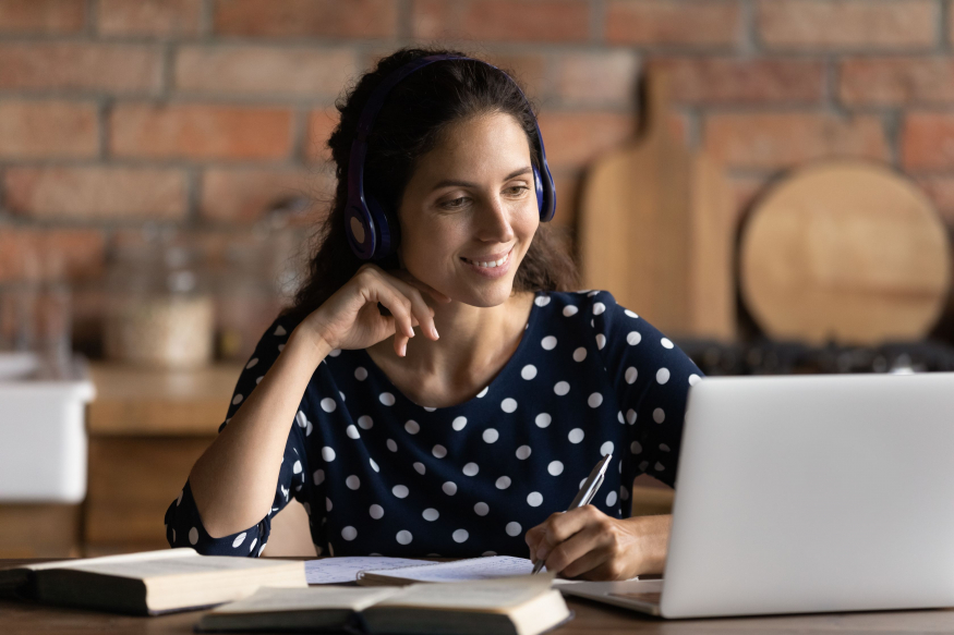 Woman taking notes in front of laptop